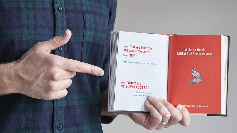 Guy pointing to a page in Essential Compendium of Dad Jokes