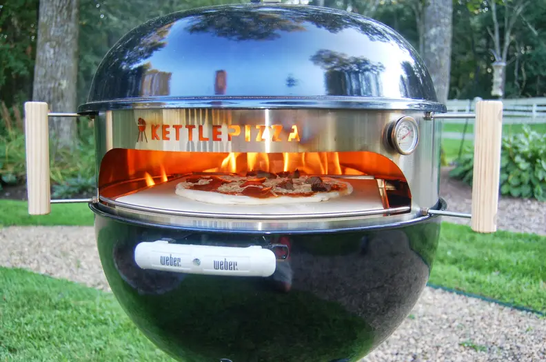 The Kettle Pizza in a Weber grill with open flame.