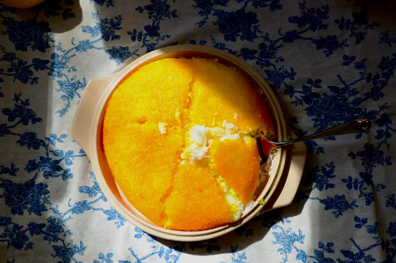 A plate of tahdig rice is placed against a blue and white backdrop.