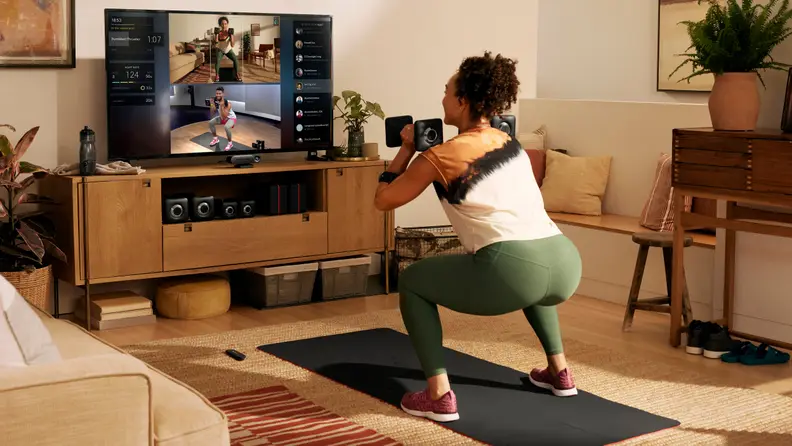 A woman doing squats with the Peloton Guide.