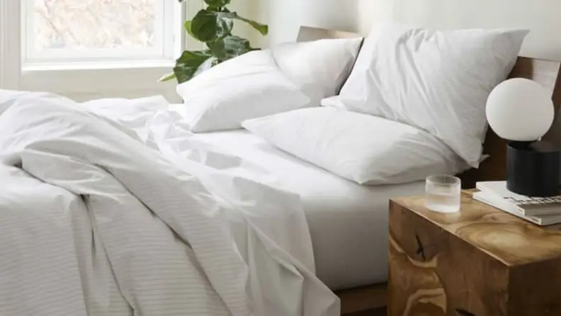 A bed with crisp white sheets and a fluffy white comforter.