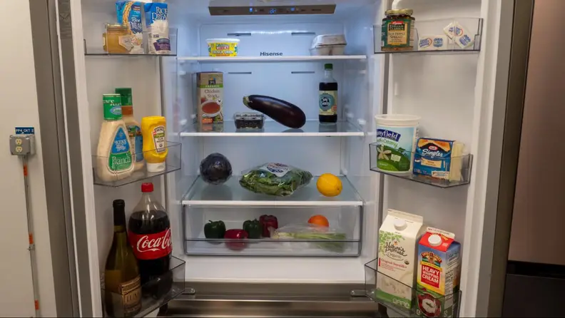 The open fridge showing off all sorts of products, produce and condiments inside.