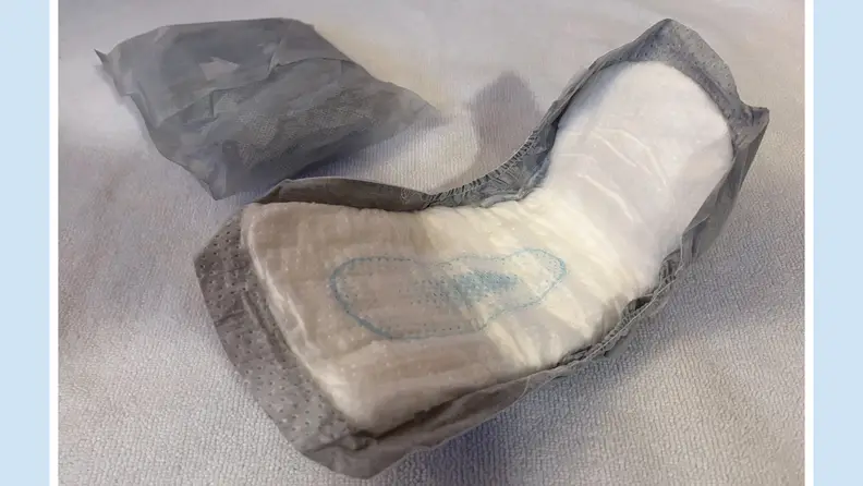 An opened Amazon Basics Maximum Absorbency Men's Guards pad next to one folded inside of its package.