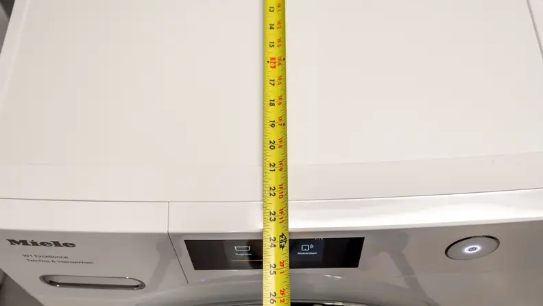 A measuring tape extends across the top of the washer, showing it's less than 24 inches deep.