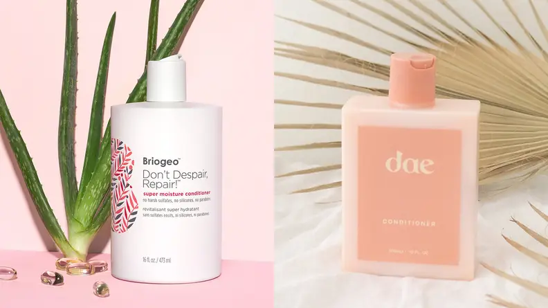On the left: The white Briogeo Don't Despair, Repair! Super Moisture Conditioner for Dry + Damaged Hair stands on a light pink background and an aloe plant is propped up behind it. On the right: The Dae Daily Conditioner stands on a fluffy white surface and a dried sun palm lays across the background.