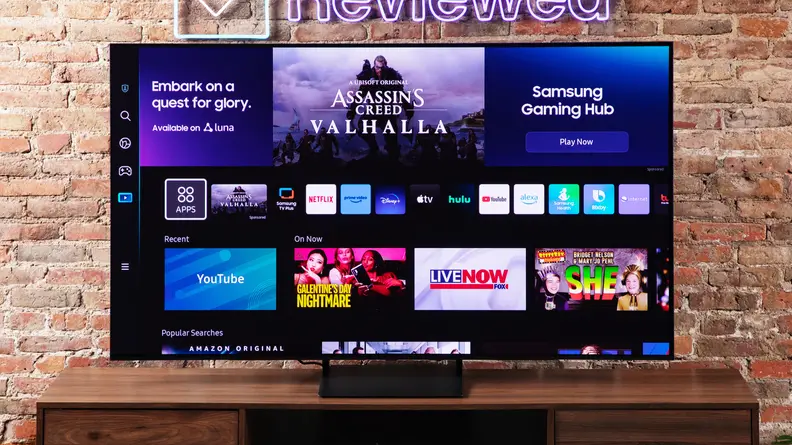 The Samsung S90C QD-OLED TV on an entertainment center with a brick background.