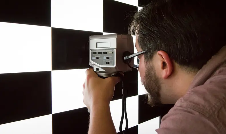A person uses a device to calibrate the color and brightness of a television screen.