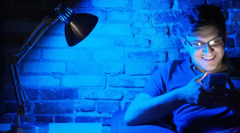 Man sitting in blue light on smartphone
