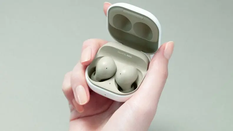 A person holds Samsung earbuds.