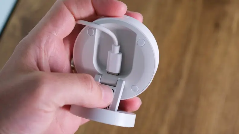 A hand holding the Aqara FP2 presence sensor showing the backside where the cord plugs in.