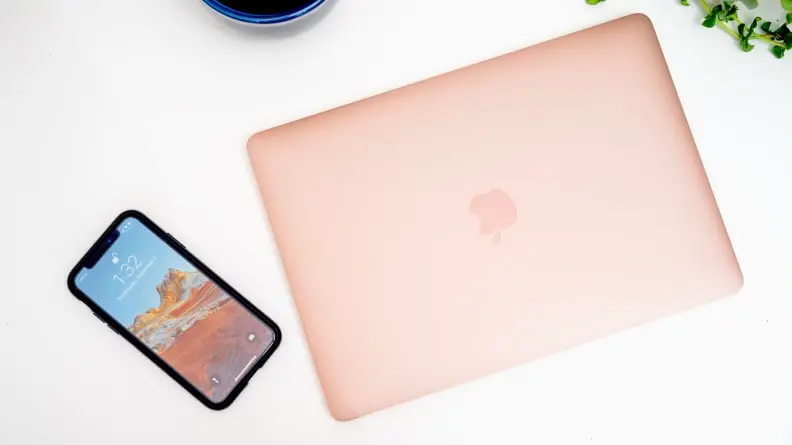 A laptop next to a cell phone on a white desk