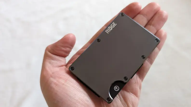 The Ridge Gunmetal Aluminum wallet being held in a hand in front of a white background.