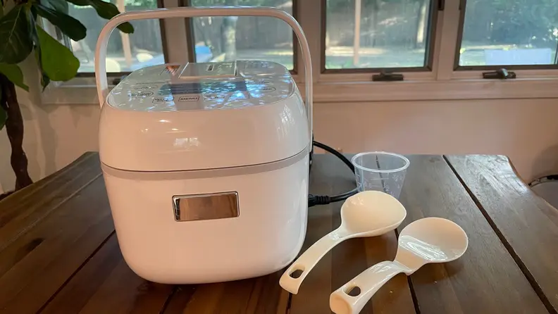Toshiba rice cooker and its accessories on a wooden surface