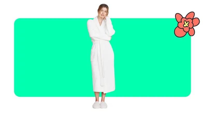 Model showcasing a white Barefoot Dreams robe and slippers with head resting on their hand.
