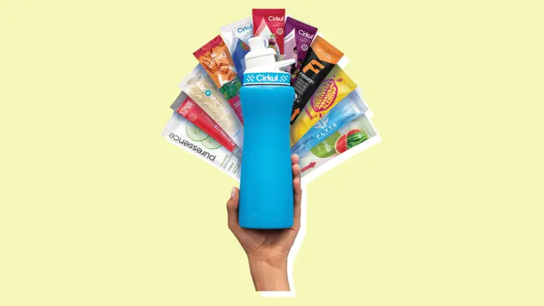 A hand holding a bottle of Cirkul with plenty of hydration packets.