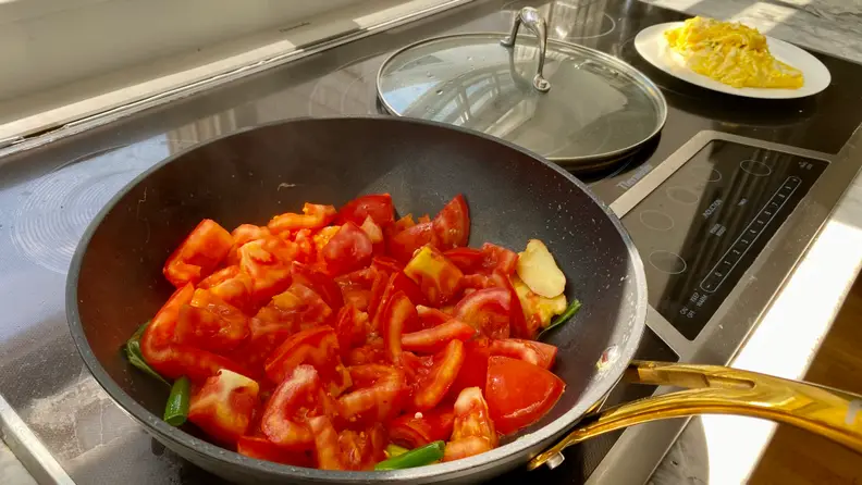 The Frök, filled to the top with diced tomatoes, is sitting on an induction cooktop.