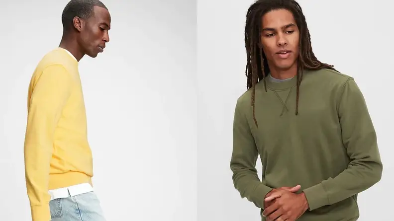 Man wearing a yellow crewneck sweatshirt, man wearing green crewneck sweatshirt from Gap while folding hands.