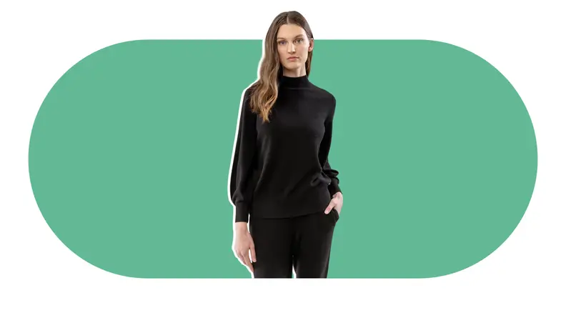 A model wearing a cashmere sweater that has a mock neck and billowing sleeves.