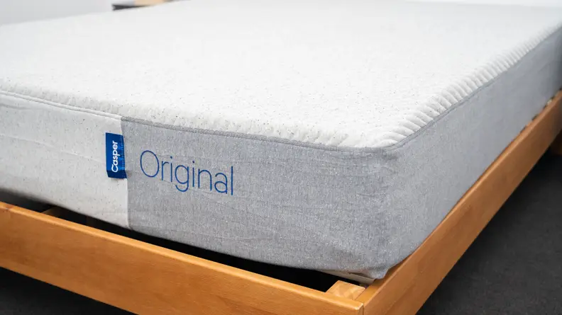 the casper original on a brown wood bed frame.