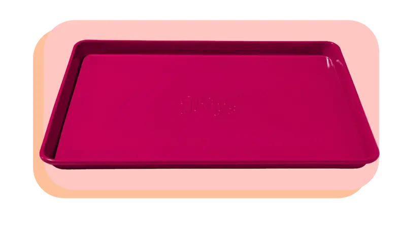 Pink Great Jones baking sheet on a light pink background.