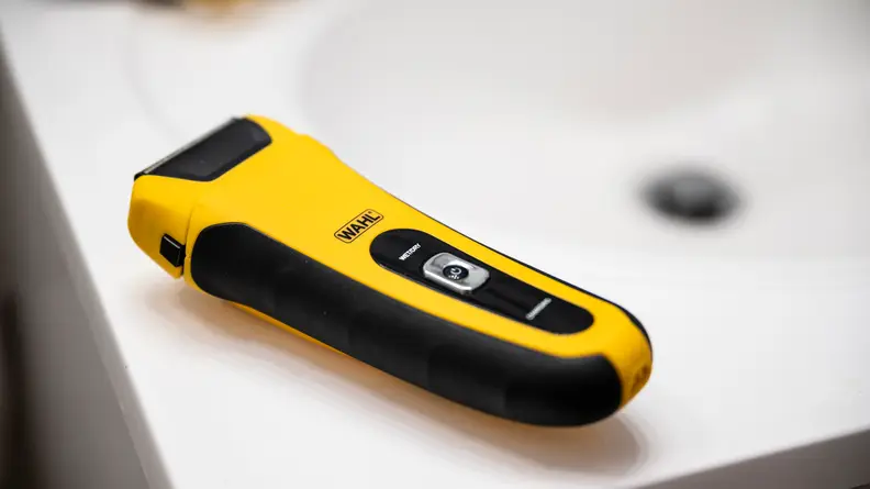 An image of a Wahl Lifeproof electric shaver sites on the lip of a white porcelain bathroom sink.