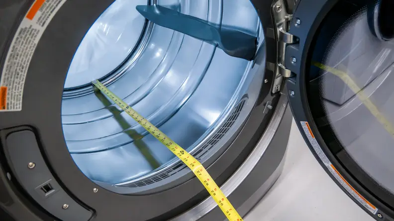 The image shows measuring tape demonstrating the size of the stainless steel drum in the Electrolux dryer.