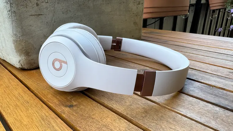 The Beats Solo 4 headphones lying flat on a wooden table.