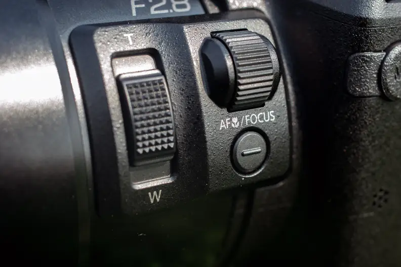 The left side of the lens has a handy focus dial and a second zoom slider–which seems unnecessary given the zoom lever attached to the shutter.