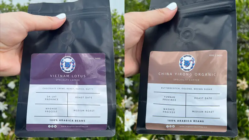 A hand holding up two coffee bean bags
