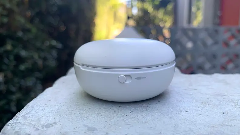 A view of the side of the T90Q earbuds case, sitting on a stone wall.