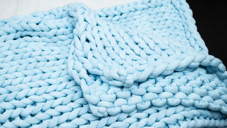 the nuzzie blanket on the corner of the bed with an edge folded up
