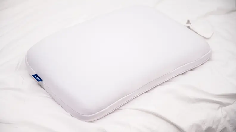Memory foam pillow laying on white mattress.