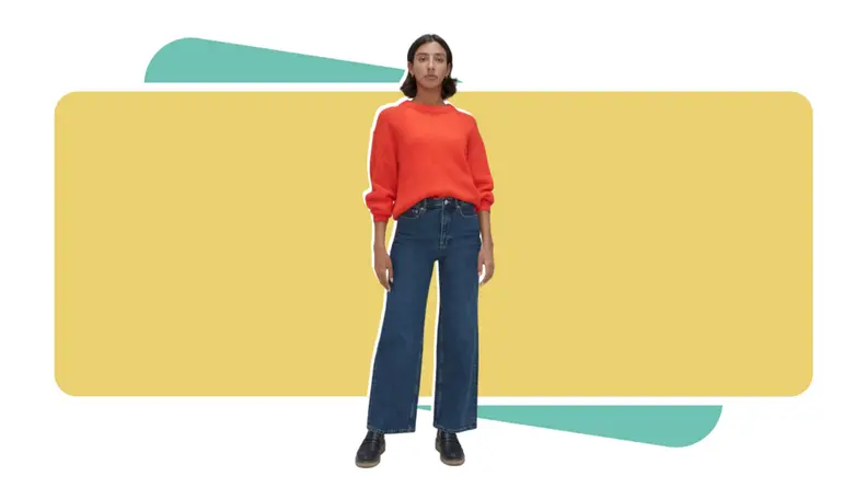 Woman wearing Everlane flare jeans and orange sweater.