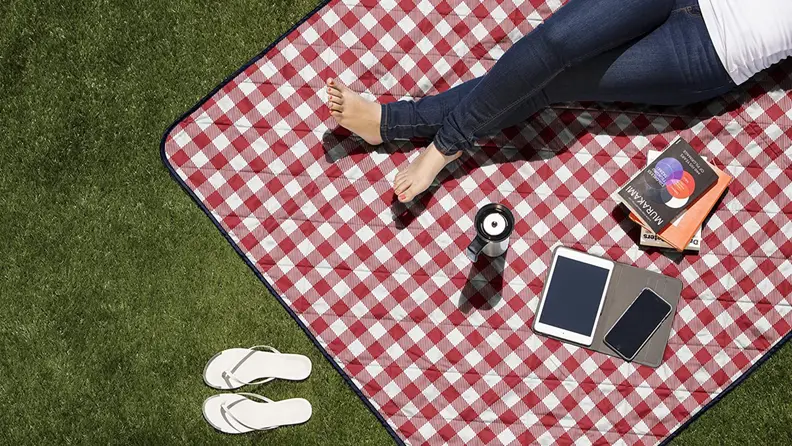 A person lays on a picnic blanket in the grass.