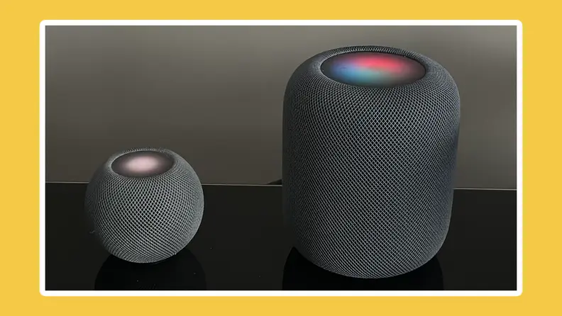 Apple HomePod mini and HomePod side by side on black surface.