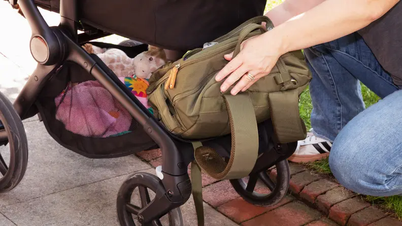 A woman taking a backpack out from underneath the Bugaboo Fox 5 stroller storage area.