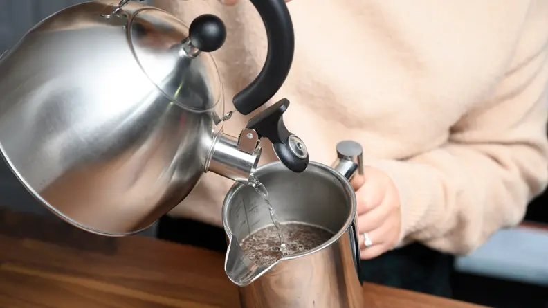 Pour the hot water over the coffee grounds.