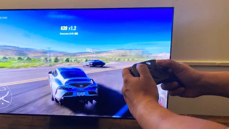 A close-up of someone's hands holding an Xbox Series X controller as they play Forza Horizon 5 via the Samsung Gaming Hub