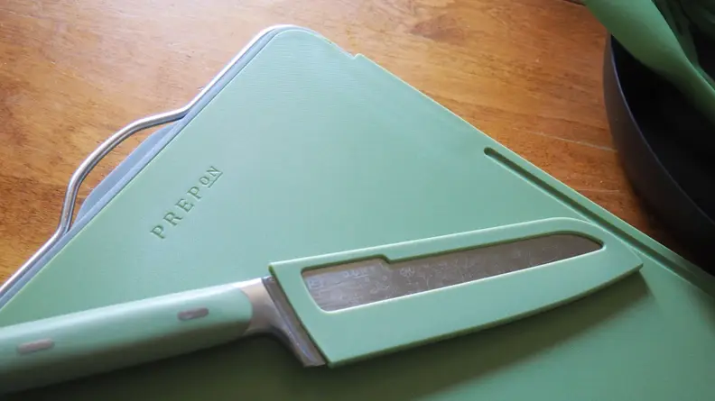 Green Santoku knife in sheath on green chopping board
