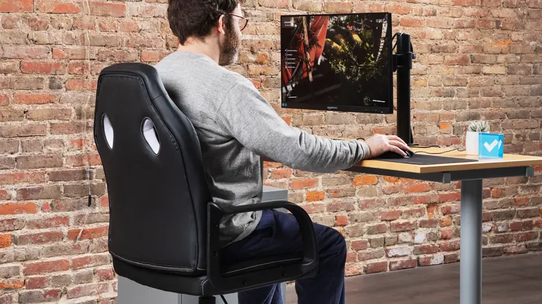 A person sitting on the Amazon Basics Racing/Gaming style office chair using a computer on a monitor.