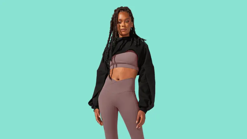 A model wearing a gray matching athletic set with a black cropped sweatshirt.