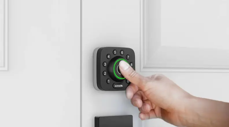 A person's hand pushing a button on a smart door lock