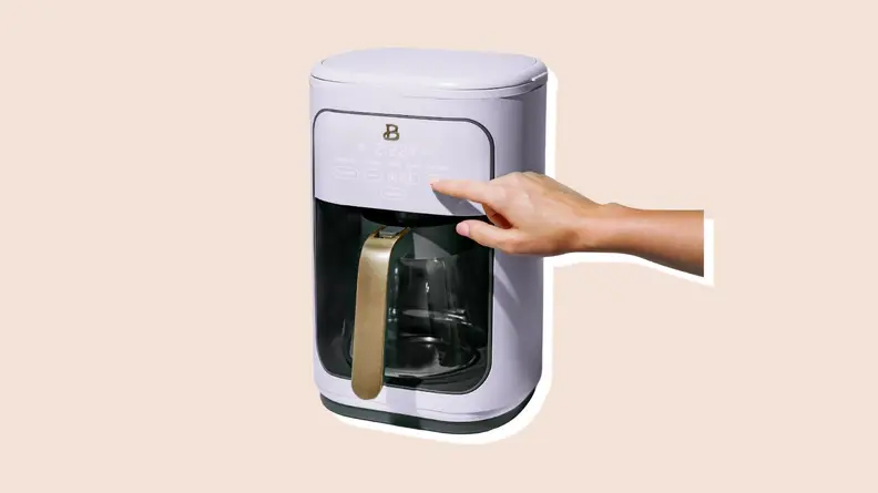 Person using finger to power on lavender-colored coffee maker from the Beautiful by Drew Barrymore Kitchen Appliances line.