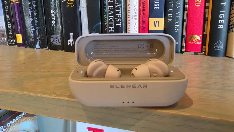 ELEHEAR Delight Hearing Aids in their case sitting on top of a bookshelf with several books in the background.