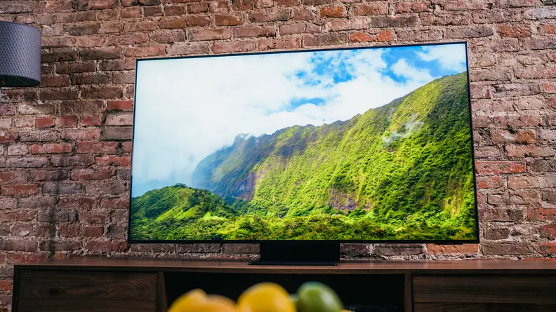 TV shows a mountain range, green against a blue sky, while clouds float overhead