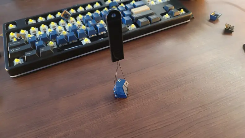 A keycap puller holding three keycaps