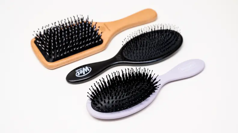 Three of the best hair brushes lay side by side on a white surface.
