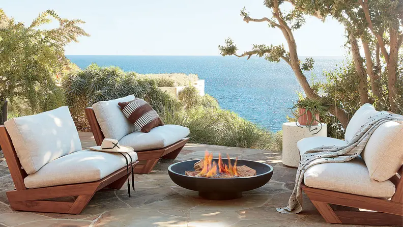 beige outdoor furniture set and fire pit next to the ocean