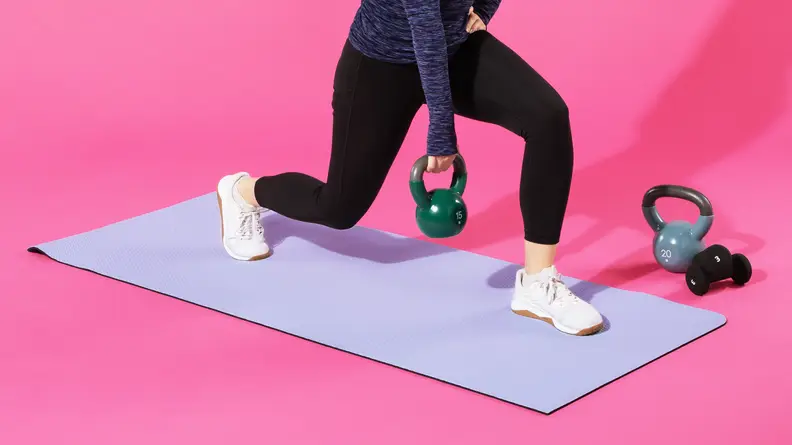 Person holding a kettlebell while doing a lunge on the purple lululemon Workout Mat.
