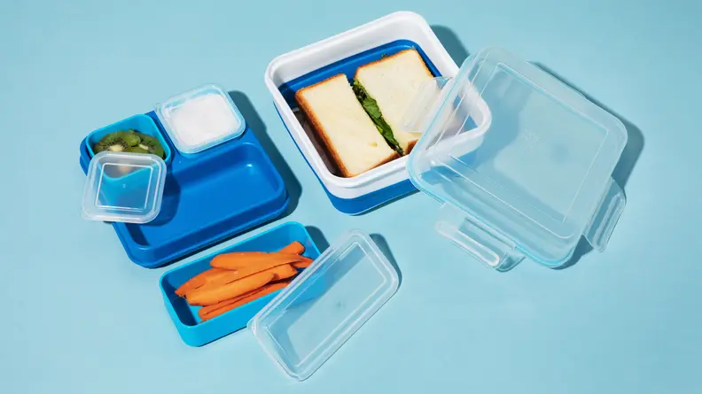 A sandwich, vegetables, fruit, and dip are stored in Bento boxes.